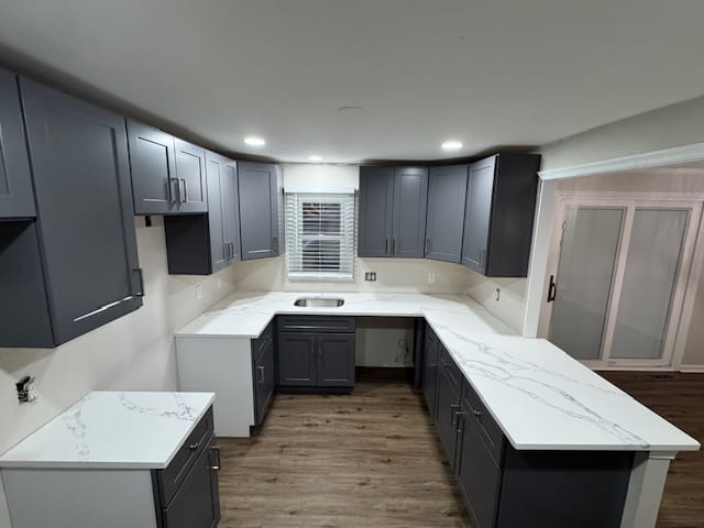 Finished U-shaped kitchen with grey cabinets, white counters and recessed ceiling lights.