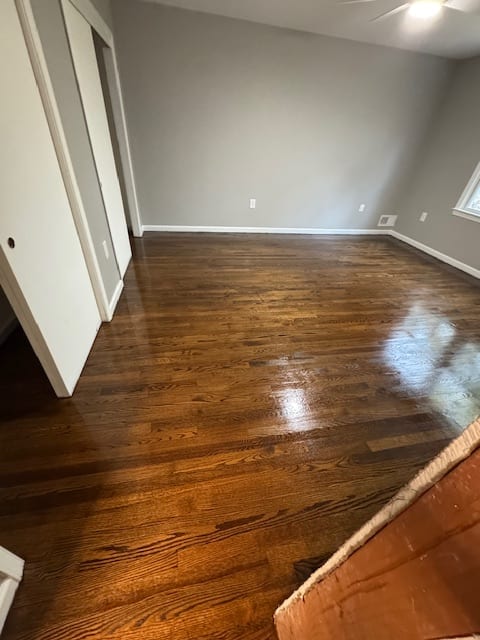 Newly refinished dark hardwood floor beside a white staircase.