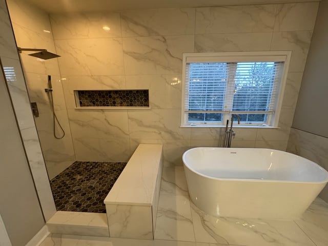 Finished primary bathroom with a freestanding white tub and large tiled walk-in shower.