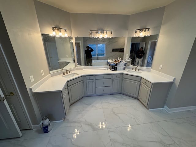 Finished bathroom with a long grey double vanity, two mirrors and bright wall lights.