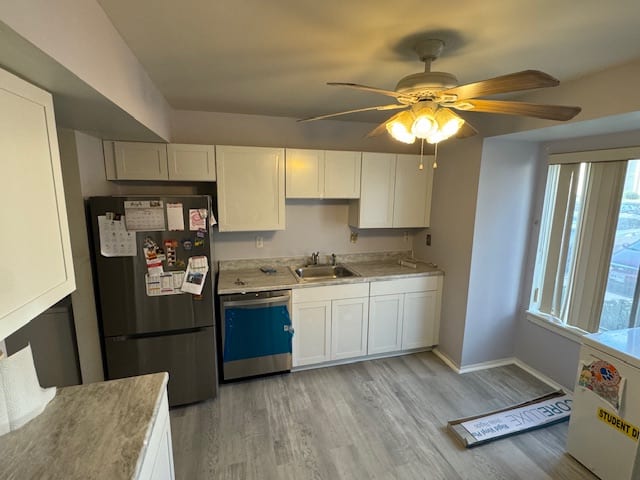 Finished compact kitchen with white cabinets, stone-look counters and pale plank flooring.