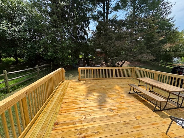 Finished pressure-treated backyard deck with perimeter railing and a wide open floor.