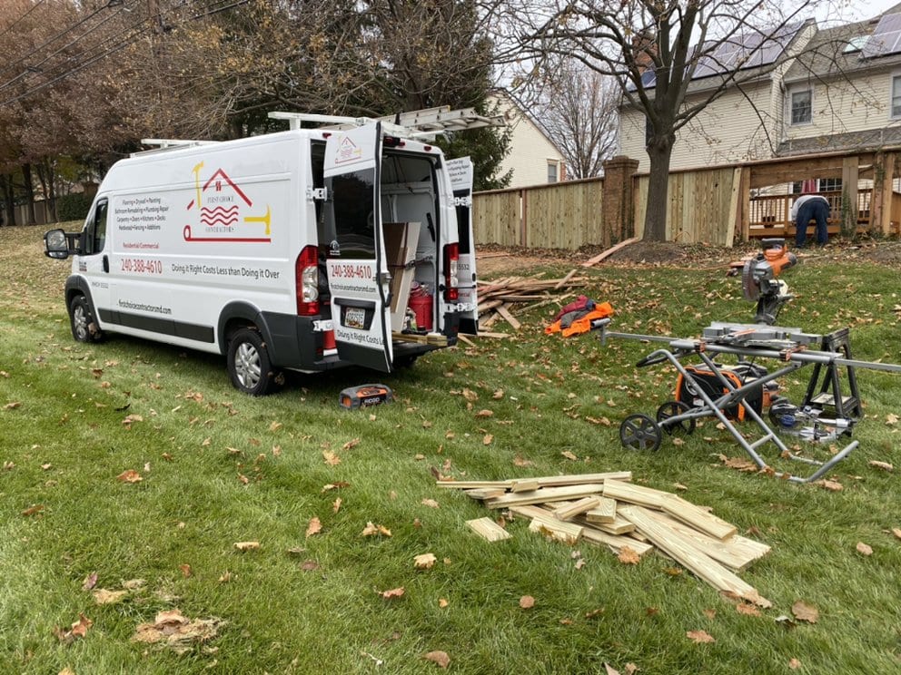 The First Choice Contractors van parked on a residential lawn with lumber, saw horses and tools laid out for a job.