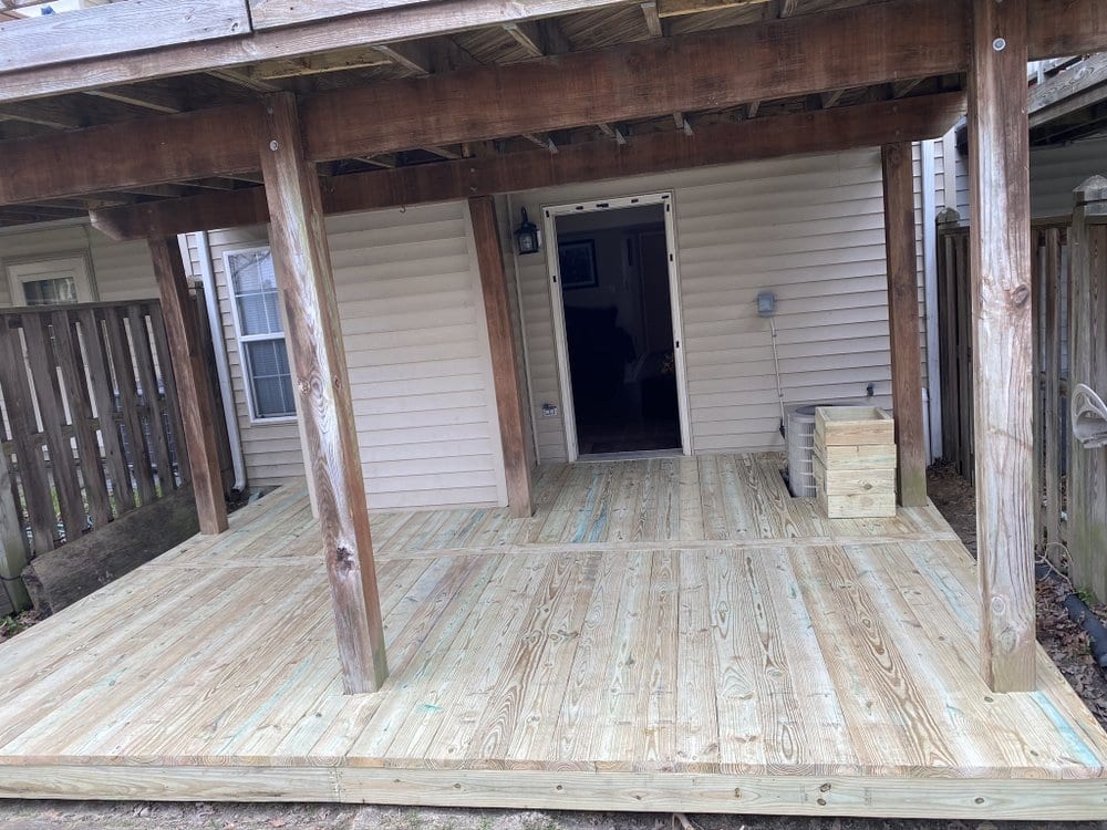 Completed timber deck with a covered roof structure supported on posts, running along the back of a house.
