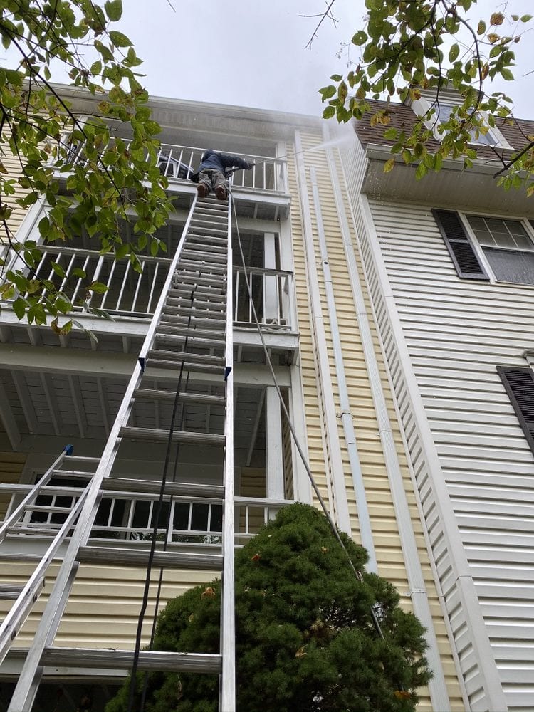 Extension ladders reaching to the top floor of a three-storey house for exterior work.