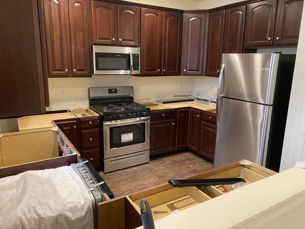 Kitchen with cherry cabinets and stainless appliances installed, packing materials still on the floor.