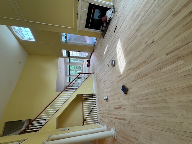 Long room with a pale hardwood floor being sanded before stain and finish.