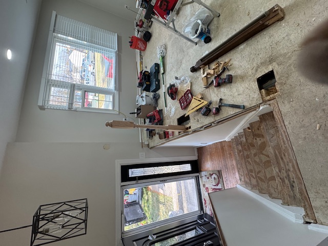 Open stair landing during installation of timber posts and dark metal balusters.