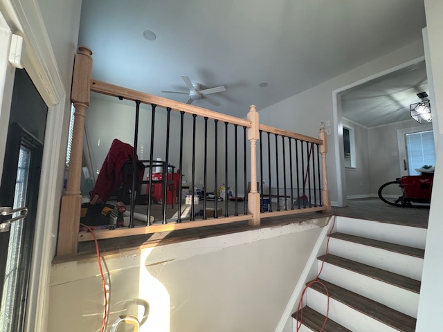 Finished open stair landing with a natural timber handrail and black metal balusters.