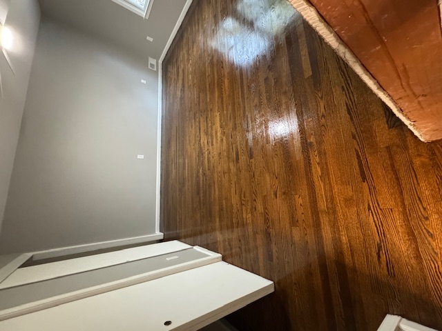 Newly refinished dark hardwood floor beside a white staircase.
