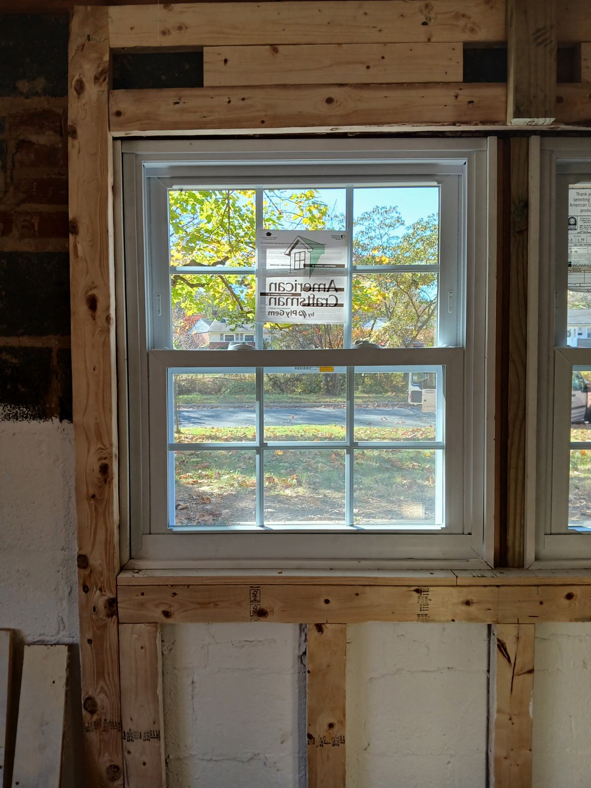 Two replacement windows set side by side in a wall with framing still visible around them.