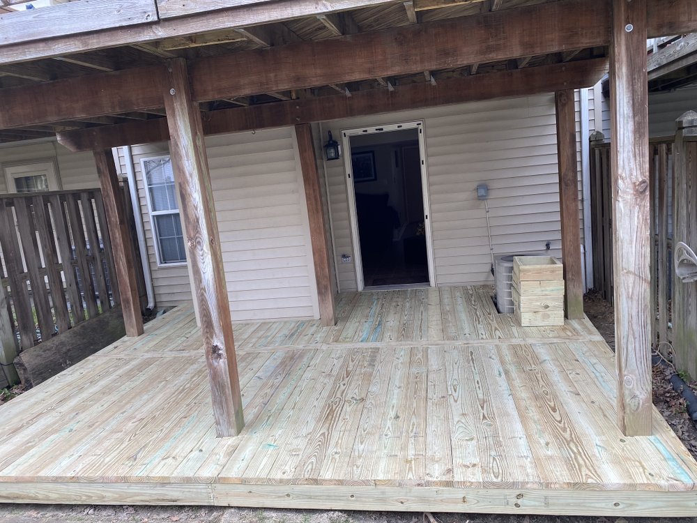 Completed timber deck with a covered roof structure supported on posts, running along the back of a house.