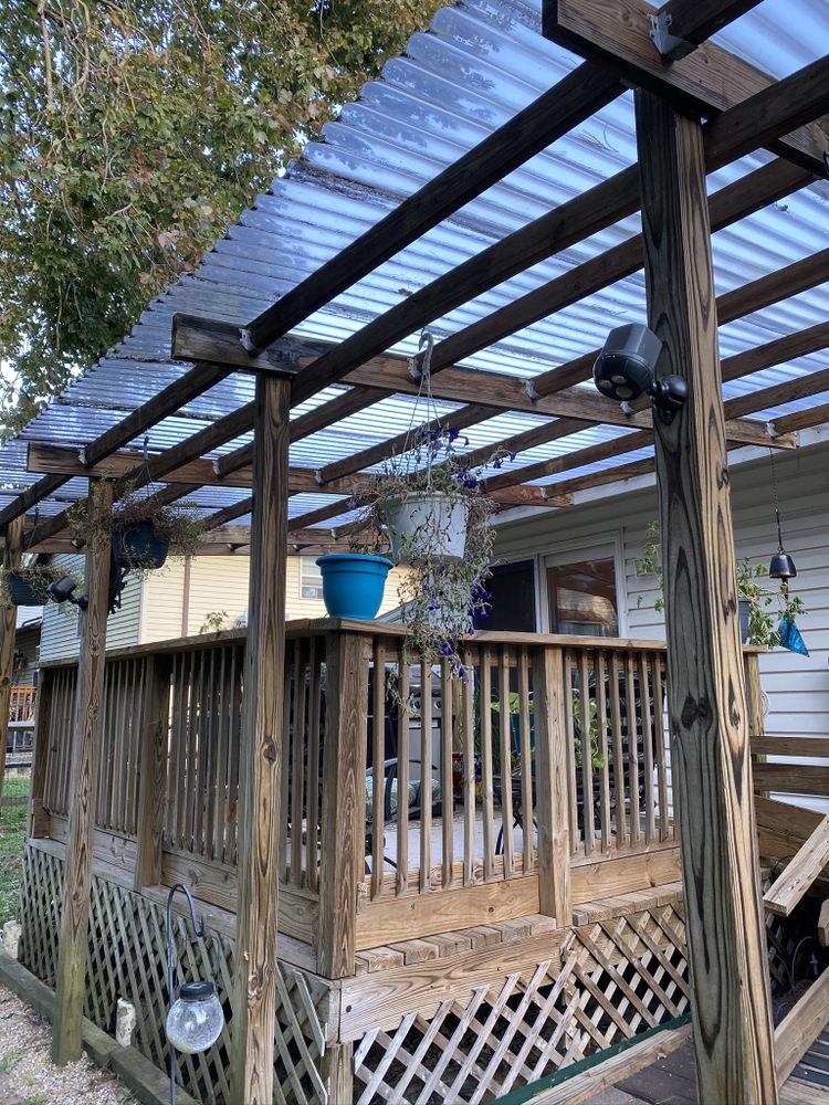 Deck with a covered roof and pergola posts, hanging planters and lattice skirting below the rail.