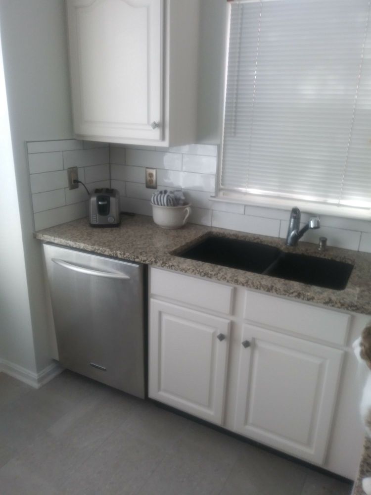 Finished kitchen corner with white cabinets, granite counter, undermount sink, dishwasher and tiled backsplash.